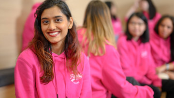 étudiante souriante entourée d'autres étudiantes dans une salle de cours NEOMA